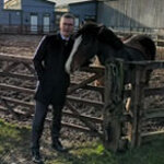 World Horse Welfare Director of Fundraising patting bay pony over wooden gate