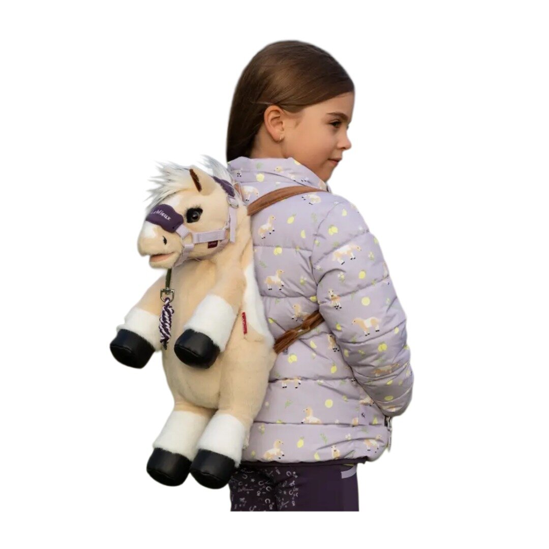 A young girl carrying a fluffy backpack of a palomino and white horse with a Le Mieux purple headcollar .